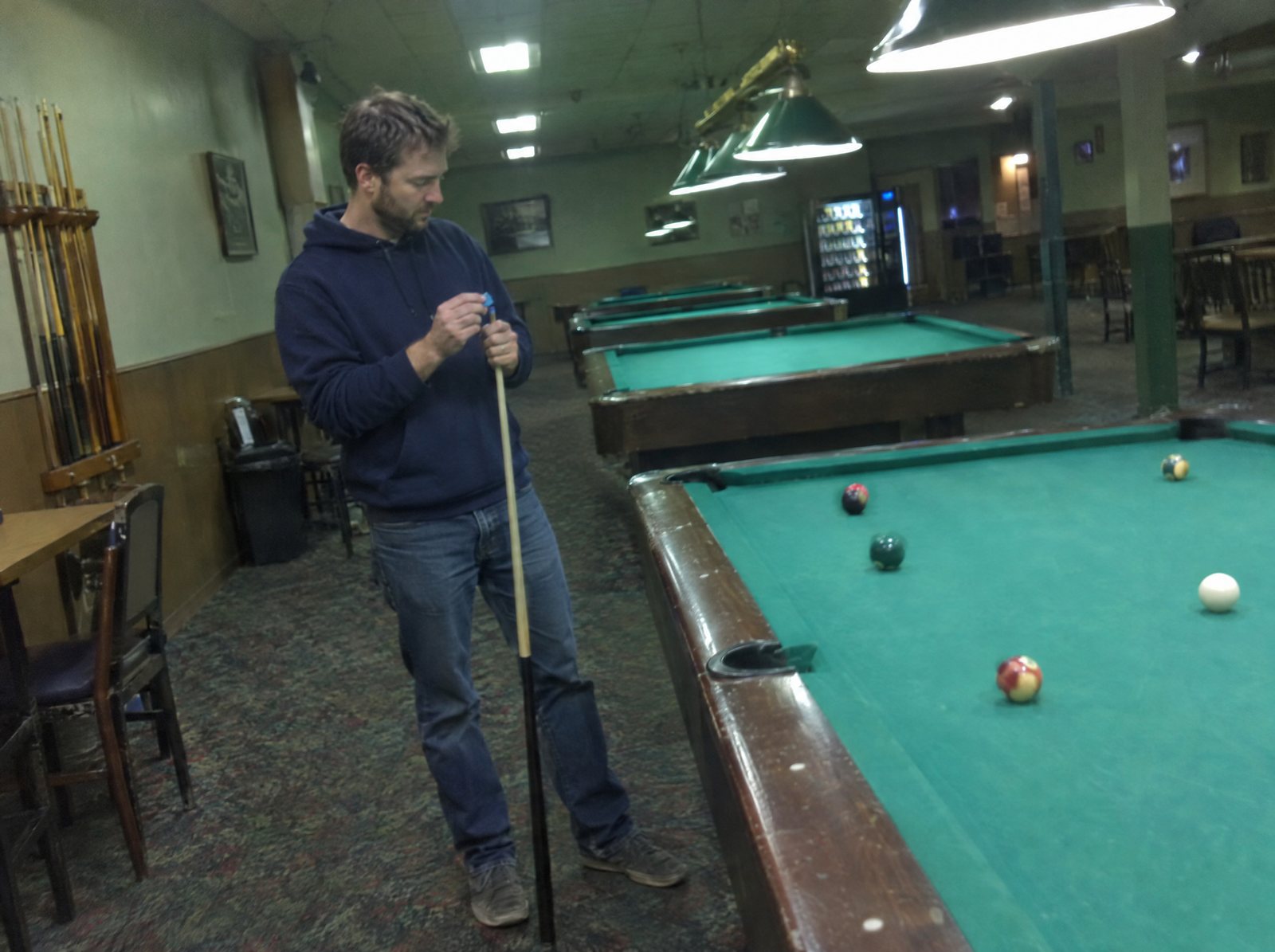 A pool player chalking a cue during a practice session